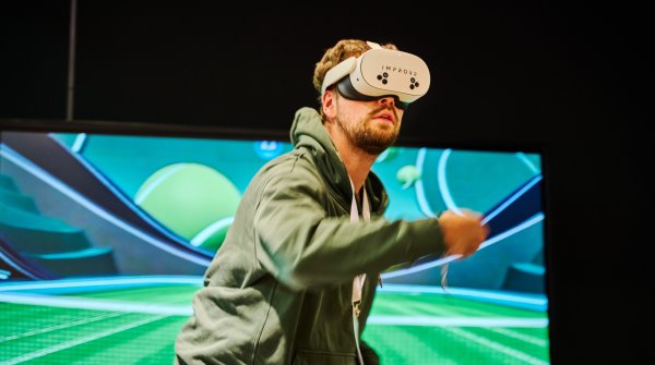 A man wears VR glasses and plays virtual tennis
